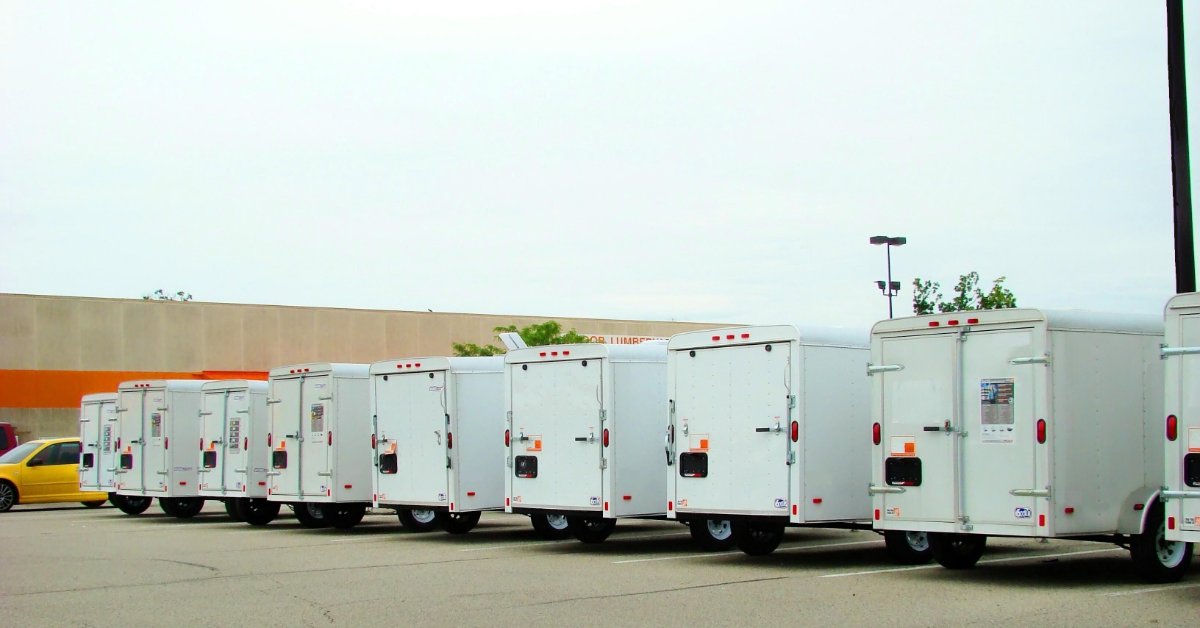 A row of white enclosed cargo trailers lined up on a dealer lot
